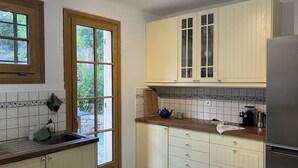 Una cucina con mobili color crema, un frigorifero in acciaio inossidabile e una finestra che si affaccia sul verde.