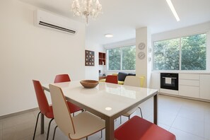 A modern kitchen with a dining area, large windows, and a built-in oven. - Charm & Green 1BR TLV - Beachside | By SweetyGuest (Tel Aviv-Yafo)