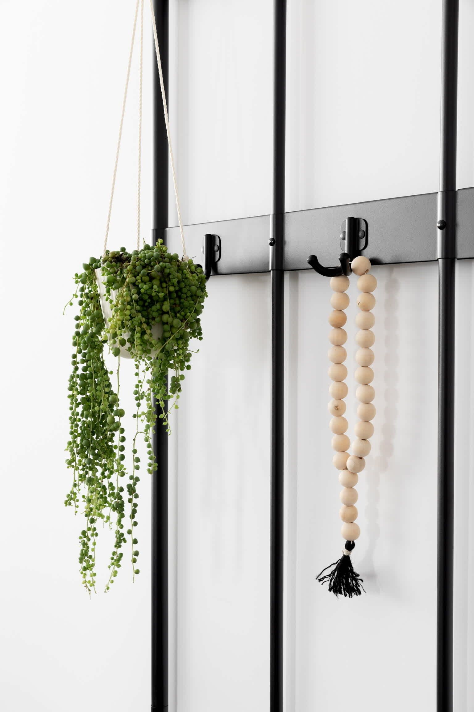 Soporte de pared para planta con una planta colgante y un adorno de cuentas.