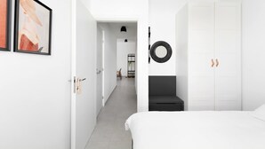 Ein modernes Schlafzimmer mit einem Bett, einem Kleiderschrank und einem Flur, der zu einem Badezimmer führt.