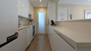 A narrow kitchen with white cabinets, a dishwasher, and a coffee machine. - ROQUET rooftop heart of Benidorm (Benidorm)