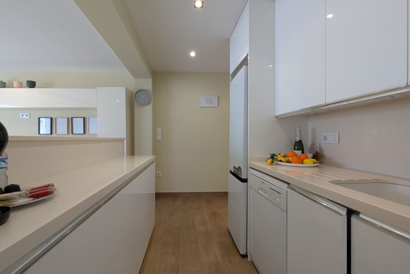 A modern kitchen with white cabinets, a dishwasher, and a fruit bowl on the counter.