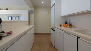 A modern kitchen with white cabinets, a dishwasher, and a fruit bowl on the counter. - ROQUET rooftop heart of Benidorm (Benidorm)