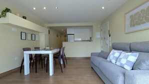 A modern apartment with a dining area, a gray sofa, and a kitchen in the background. - ROQUET rooftop heart of Benidorm (Benidorm)