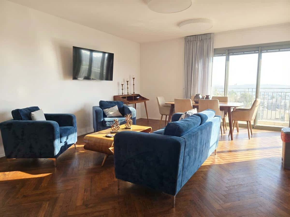 Ein modernes Wohnzimmer mit einer Sofagarnitur, einem Couchtisch und einem an der Wand befestigten Fernseher.