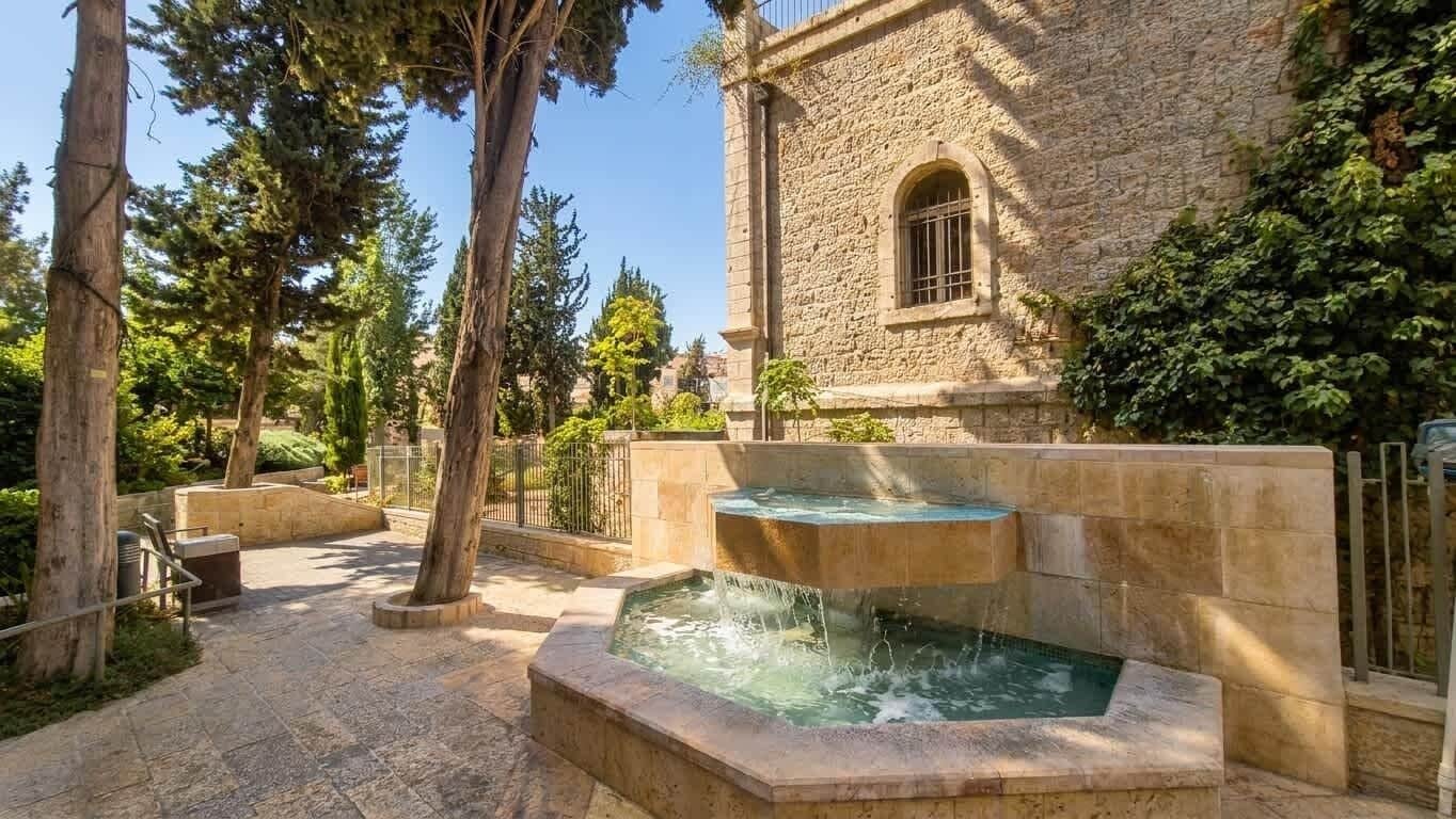 A stone building with a fountain and a paved courtyard.