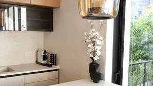 Eine moderne Küche mit weißer Arbeitsplatte, einer schwarzen Induktionskochplatte, Holzschränken und einer hängenden Pendelleuchte.