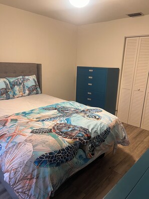 Une chambre à coucher avec un lit, une commode bleue et une armoire.