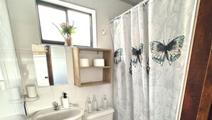 Un baño con lavamanos, inodoro y cortina de ducha con diseños de mariposas.