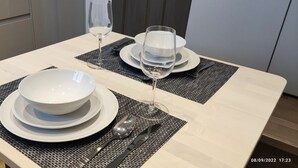 Una mesa de comedor dispuesta con platos blancos, tazones, cubiertos y copas de vino, con un sello de fecha de 08/09/2022 17:23.