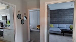 Una cocina moderna con armarios blancos, una cafetera y un comedor con un sofá y una silla amarilla.