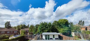 Un quartier résidentiel avec des maisons, un petit bâtiment doté d’un toit plat et un ciel bleu dégagé parsemé de nuages.