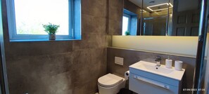 Een badkamer met toilet, wastafel en een raam met een plant.