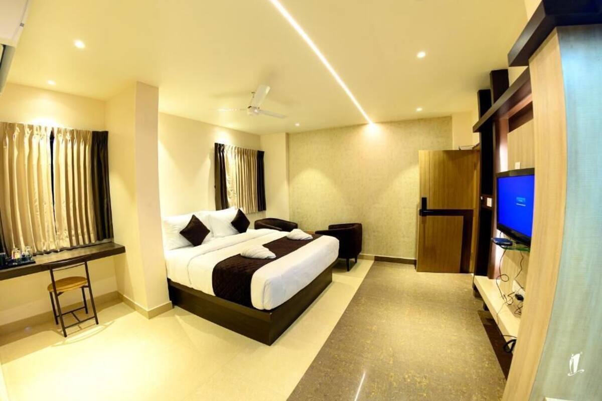 Quarto de hotel moderno com uma cama grande, uma escrivaninha, uma TV e um ventilador de teto.