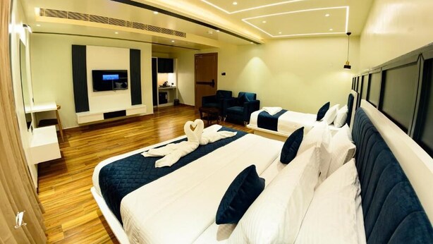 Une chambre d’hôtel moderne dotée d’un grand lit, d’une télévision, d’un coin salon et d’une kitchenette.