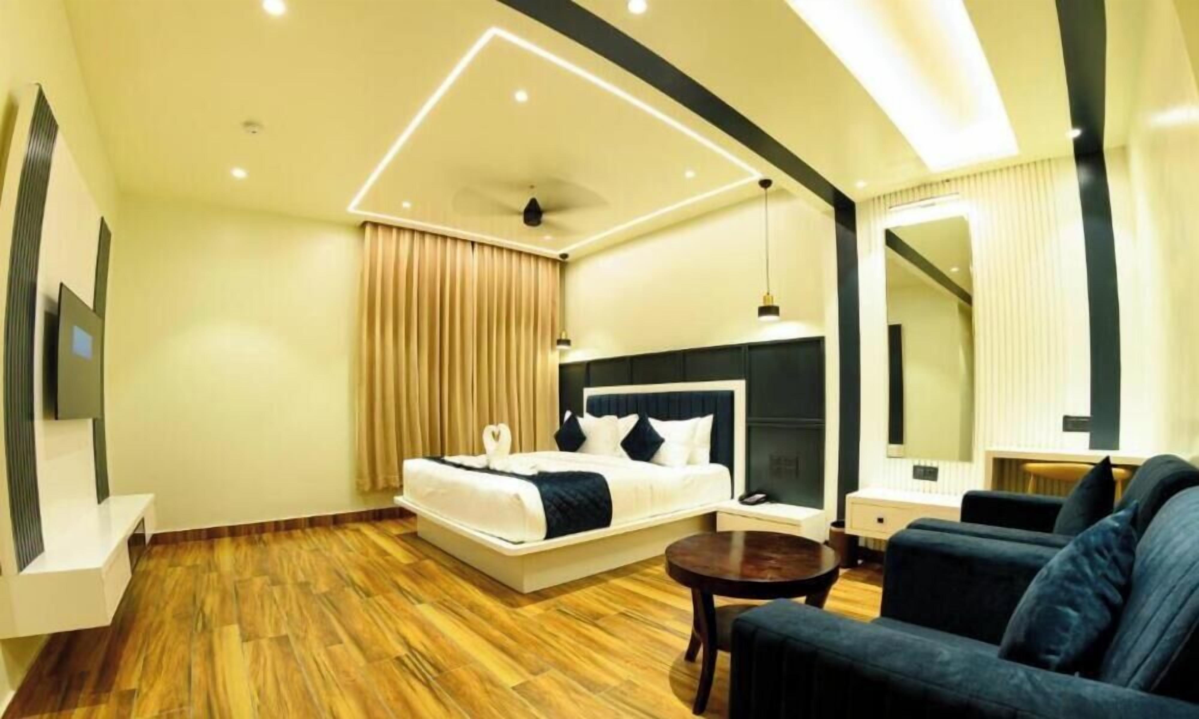 Una habitación de hotel moderna con una cama, un sofá, una mesita y un espejo.