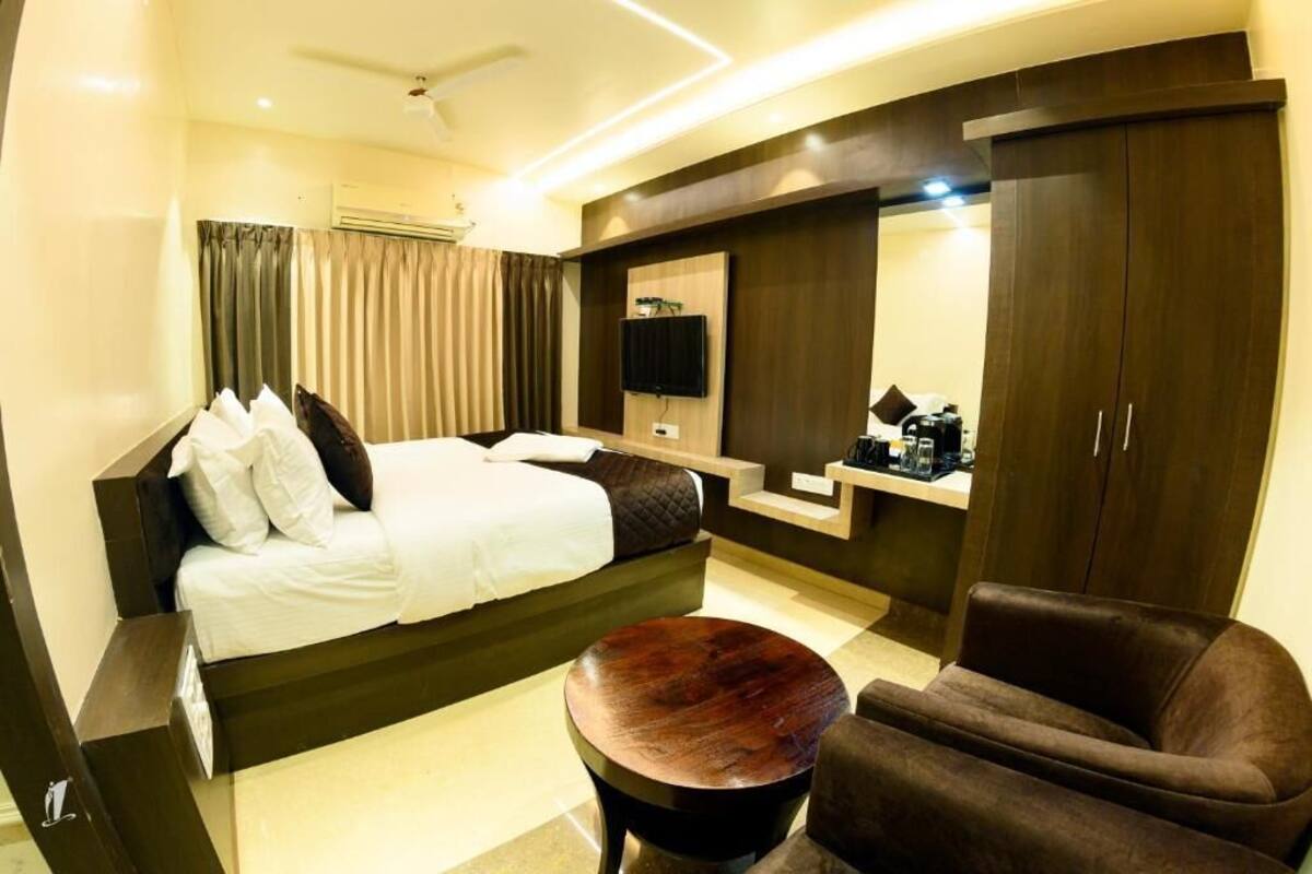 Quarto de hotel moderno com cama, área de estar, televisão e guarda-roupa.