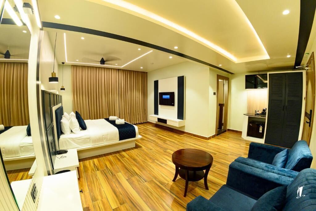 Una habitació d'hotel moderna amb un llit, un sofà, una televisió i una taula petita.