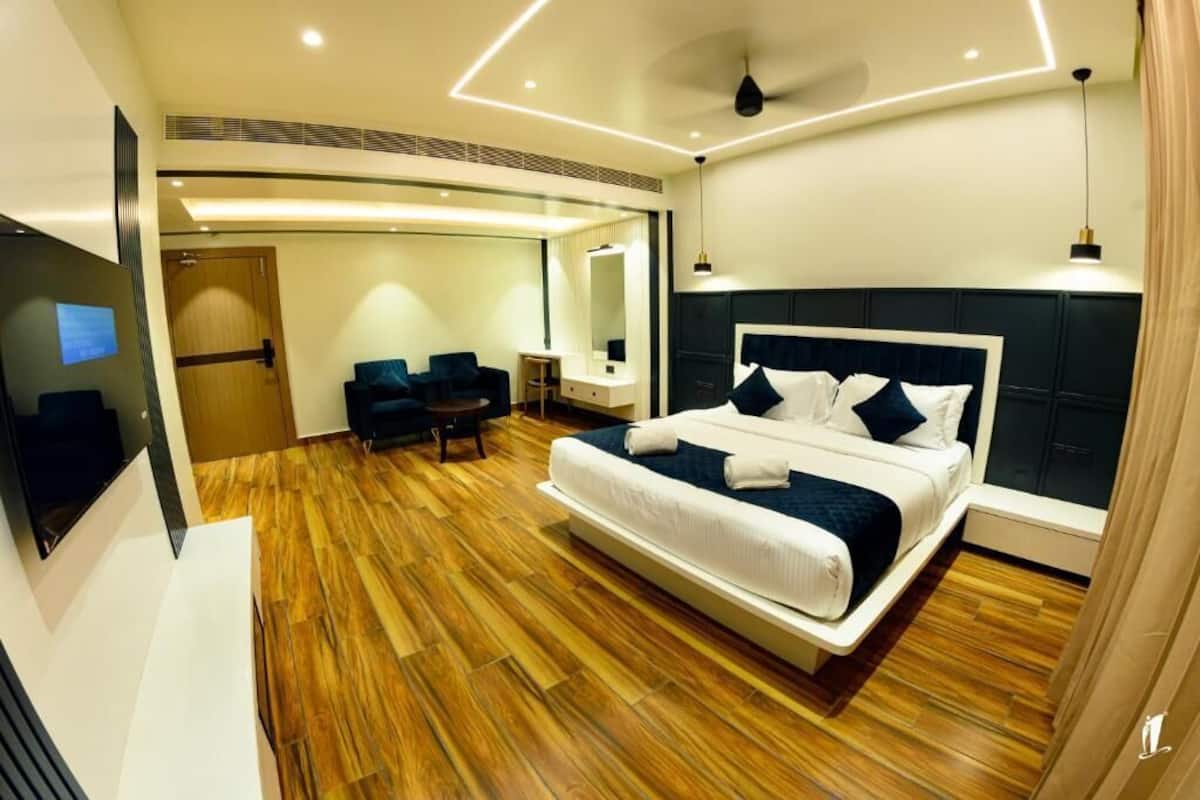 Quarto de hotel moderno com uma cama grande, televisão, escrivaninha e cadeira.