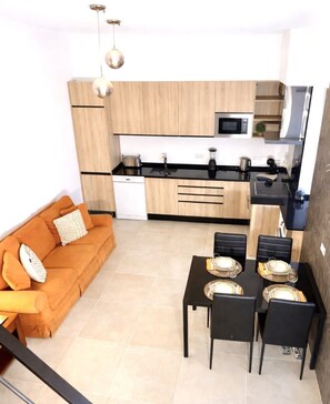 A compact living space with a kitchenette, a dining area, and a sofa. - House 20- Ideal house for families- 10 minutes from Vilamoura and Quinta do Lago (Faro)