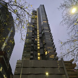 A tall, modern skyscraper with a unique stepped design, featuring numerous windows and balconies. - Deluxe 2BR apt Excellent Location Cityviews & Pool (Melbourne)