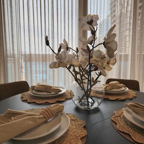 A dining table set with plates, napkins, and a vase with white flowers. - Deluxe 2BR apt Excellent Location Cityviews & Pool (Melbourne)