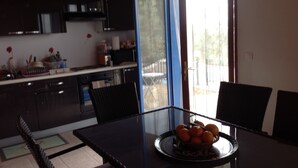 Een moderne keuken met donkere kastjes, een glazen eettafel en een schaal oranjes op de tafel.