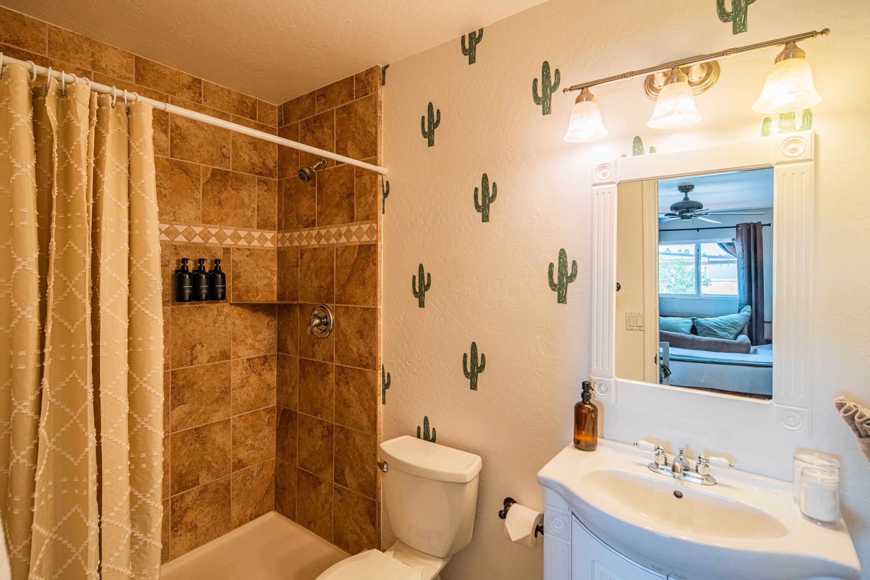 A bathroom with a shower, toilet, sink, and mirror.