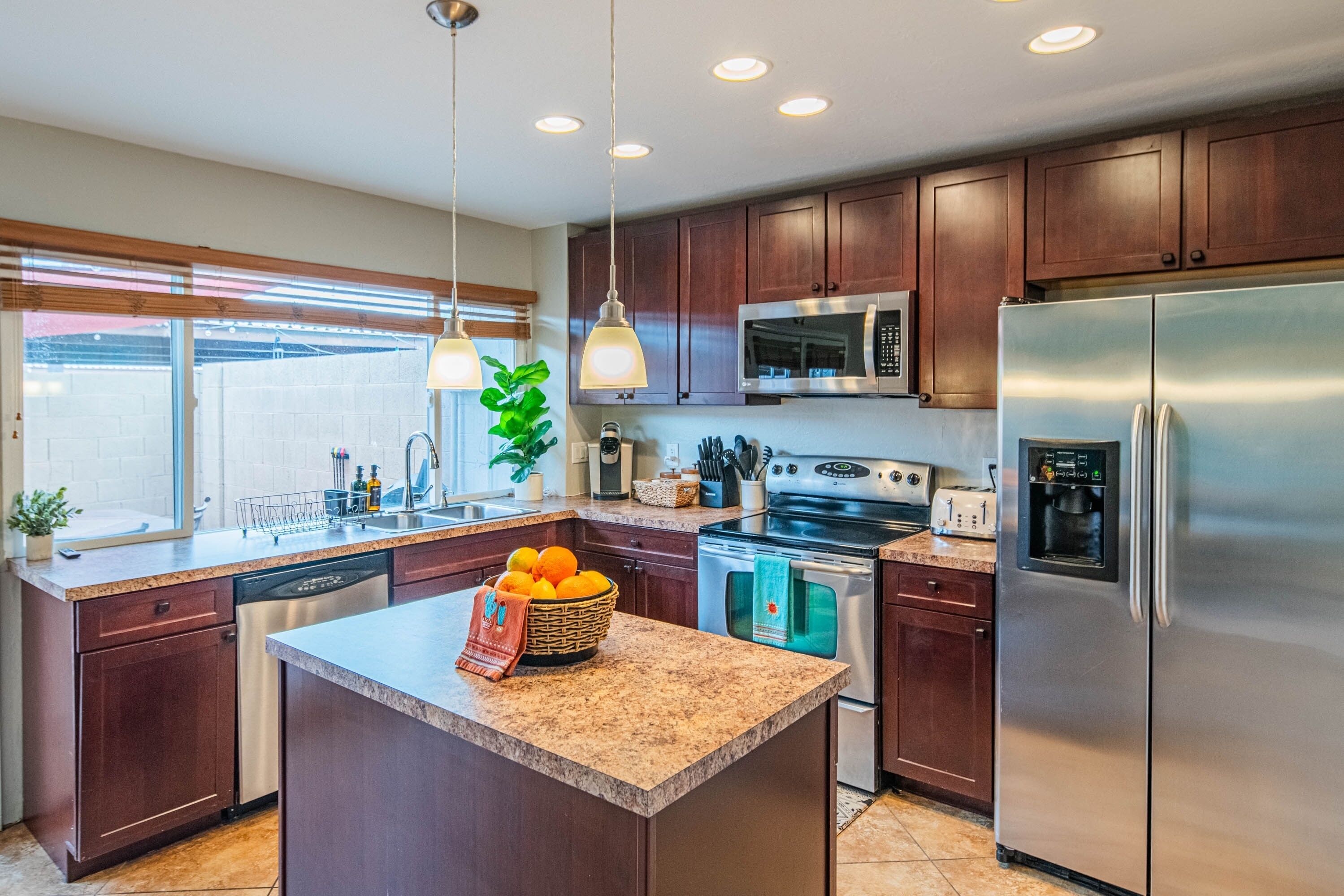 A modern kitchen with dark wooden cabinets, stainless steel appliances, and a granite countertop.