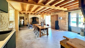 A rustic interior with exposed wooden beams, a stone wall, a fireplace, and a dining area with chairs and a table. - Where authenticity meets the comforts of today.Includes covered private terrace (Blanquefort-sur-Briolance)