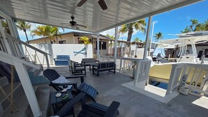 A covered outdoor area with lounge chairs and a pool. - Spacious 3 Bedroom, 2 Bath Canal Home in the Heart of Tavernier (Tavernier)