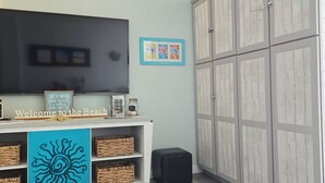 Habitación con televisor, cartel de bienvenida, cestas de mimbre y un armario.