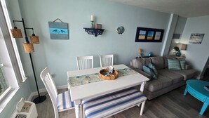 Una sala de estar con una mesa de comedor, sillas, un sofá y una mesita auxiliar.