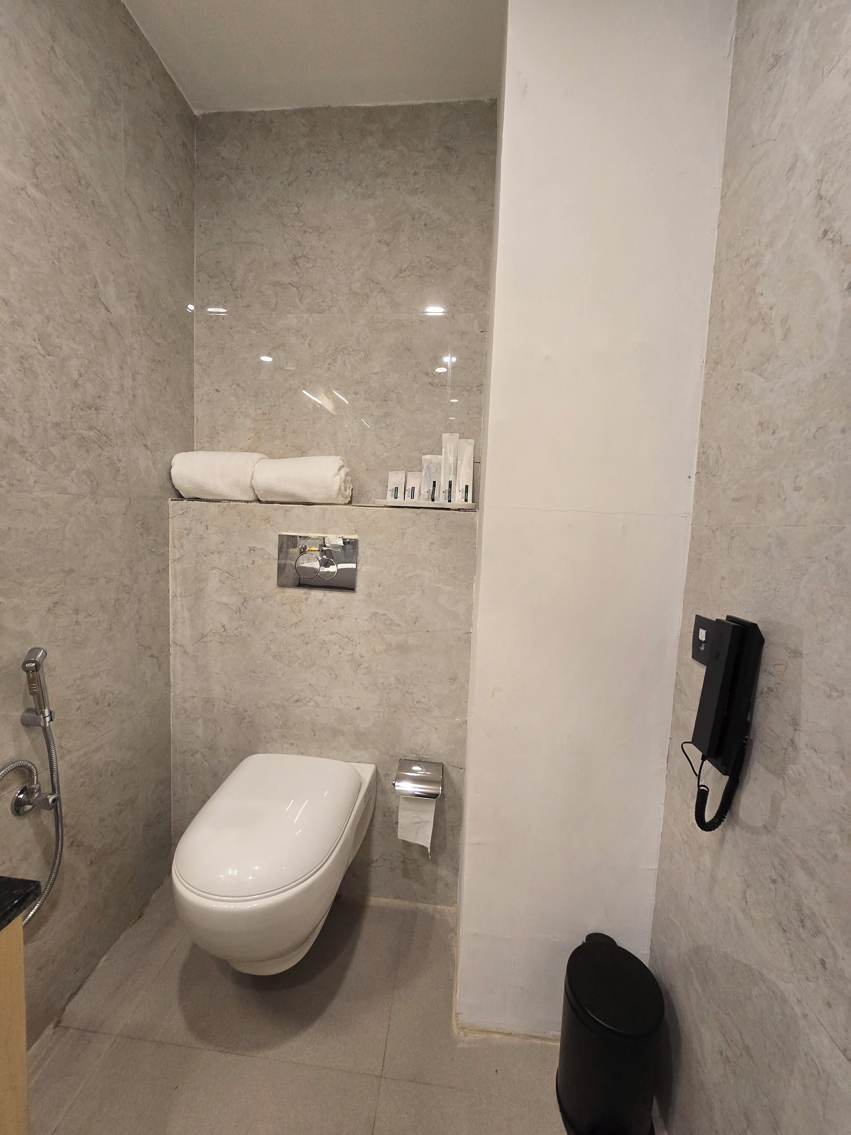 Un baño moderno con inodoro, ducha, toallero y dispensador de papel higiénico.