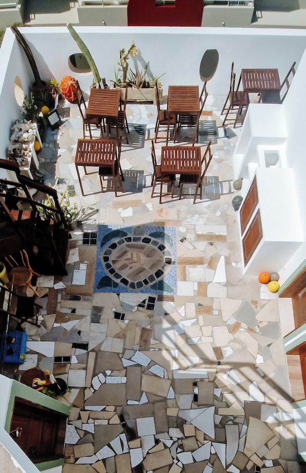 A courtyard with a mosaic floor, wooden furniture, and potted plants.