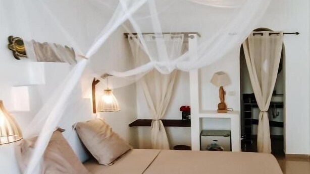 Een slaapkamer met hemelbed, nachtkastjes en een kledingkast.