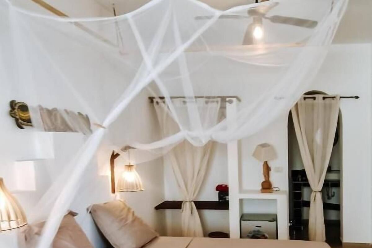 A bedroom with a canopy bed, bedside tables, a nightstand, and a wardrobe.