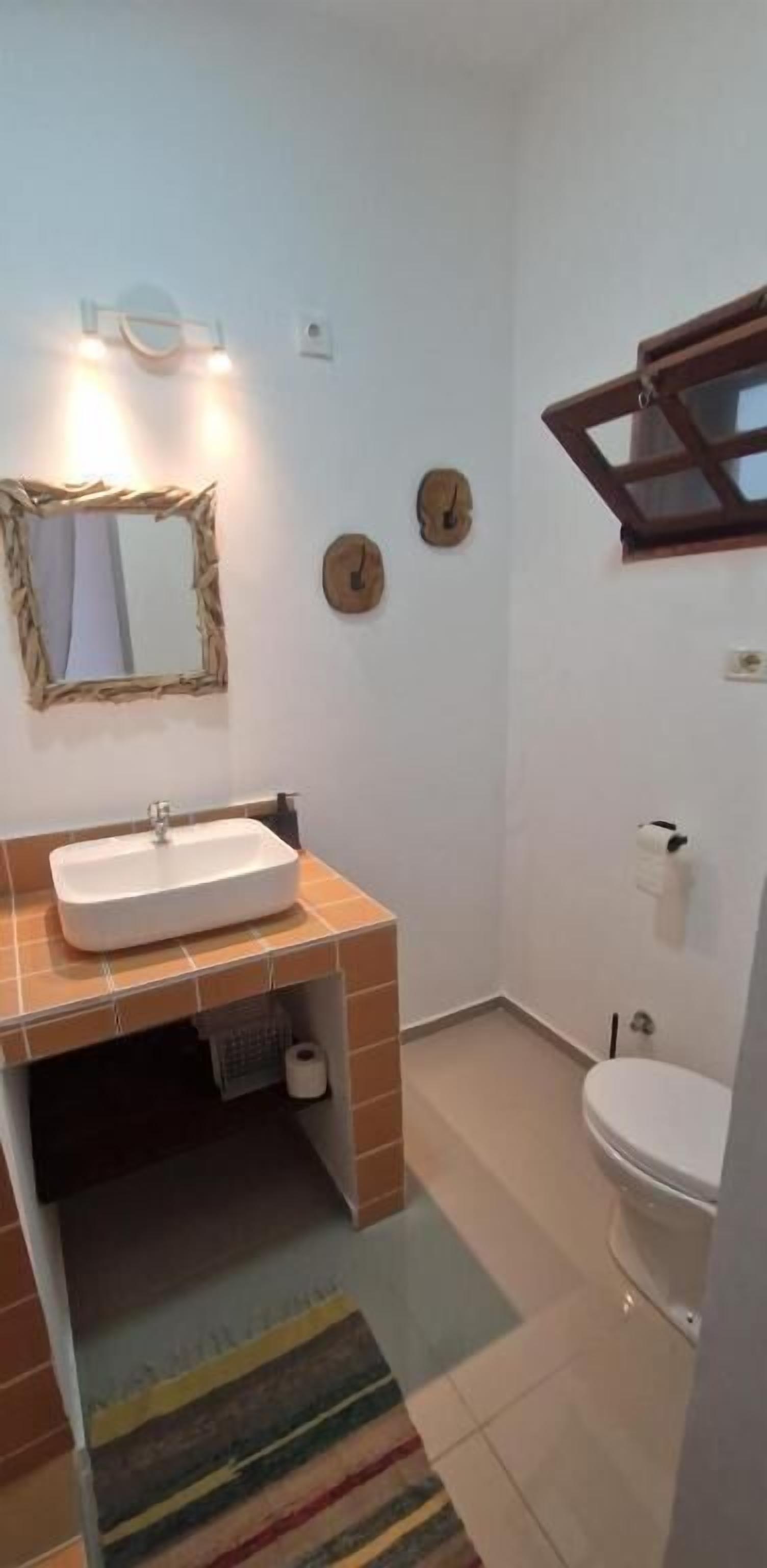 Un baño con lavamanos, inodoro y espejo.
