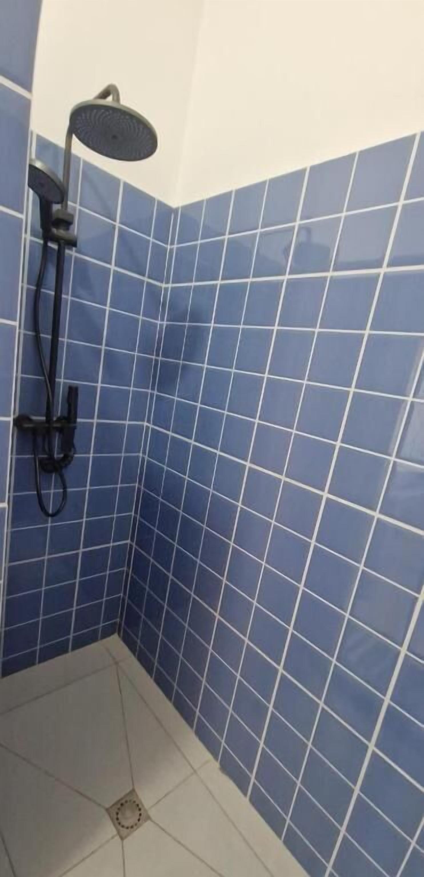 Een badkamer met blauwe betegelde wanden en een douche.