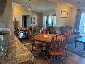A dining area with a round table, wooden chairs, and a kitchen counter. - Cozy 2-bedroom condo in fantastic Pointe Royale Branson location (Branson)