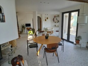 A spacious living area with a round wooden table and chairs, a television, and potted plants. - Character house, between Aix-en-Provence and the Lubéron (Saint-Cannat)