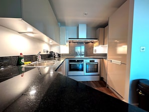 A modern kitchen with a granite countertop, stainless steel appliances, and a built-in oven. - Central London Riverside Apartment (London)