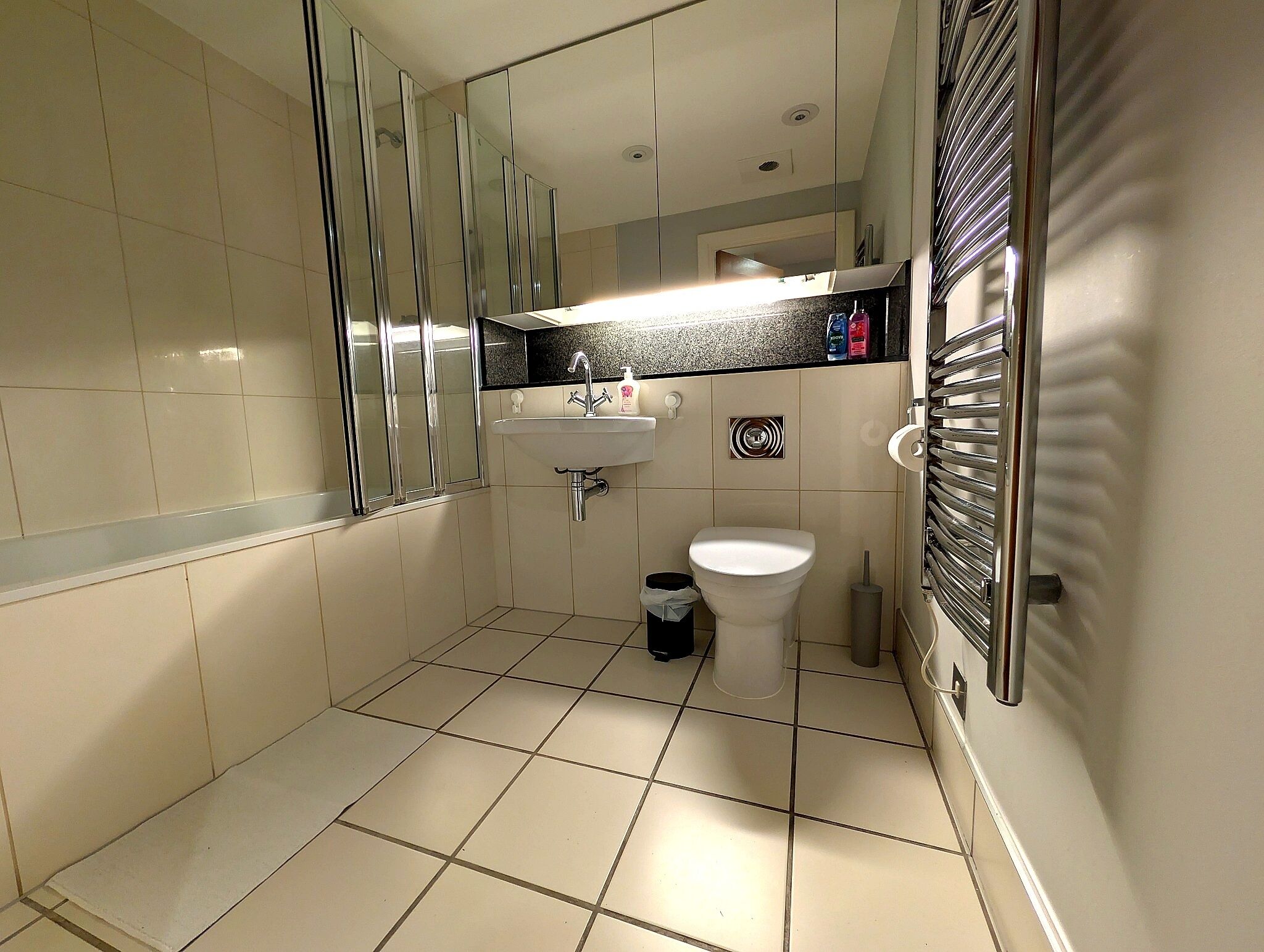 Een badkamer met toilet, wastafel en spiegel.
