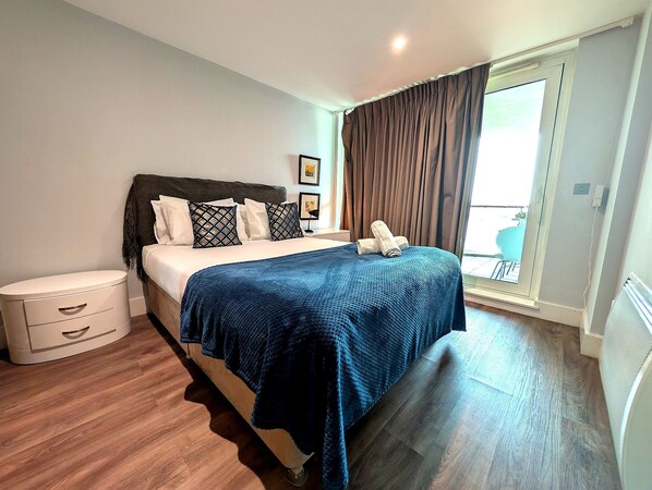 A bedroom with a bed, bedside table, and a view of the outside. - Central London Riverside Apartment (London)
