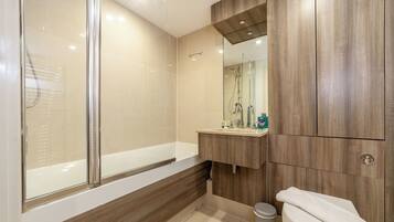 Ein modernes Badezimmer mit einer Glaskabine zur Dusche, einem Holzlagerraum und einer Toilette.