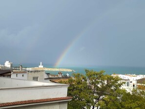 Küstliche Ansicht mit Leuchtturm, Regenbogen und Gebäuden.