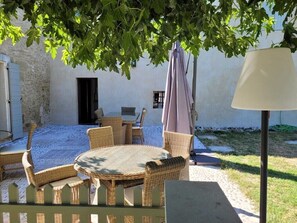 An outdoor seating area with wicker furniture, a table, and a lamp. - 18th century Provencal farmhouse - semi-detached - with exclusive pool area (Saint-Étienne-du-Grès)