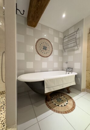 A bathroom with a freestanding bathtub, a towel rack, and a patterned floor. - 18th century Provencal farmhouse - semi-detached - with exclusive pool area (Saint-Étienne-du-Grès)