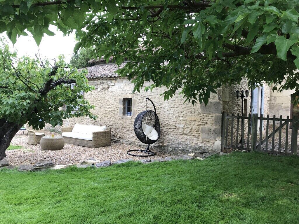 A stone building with a tiled roof, a hanging chair, and outdoor furniture.