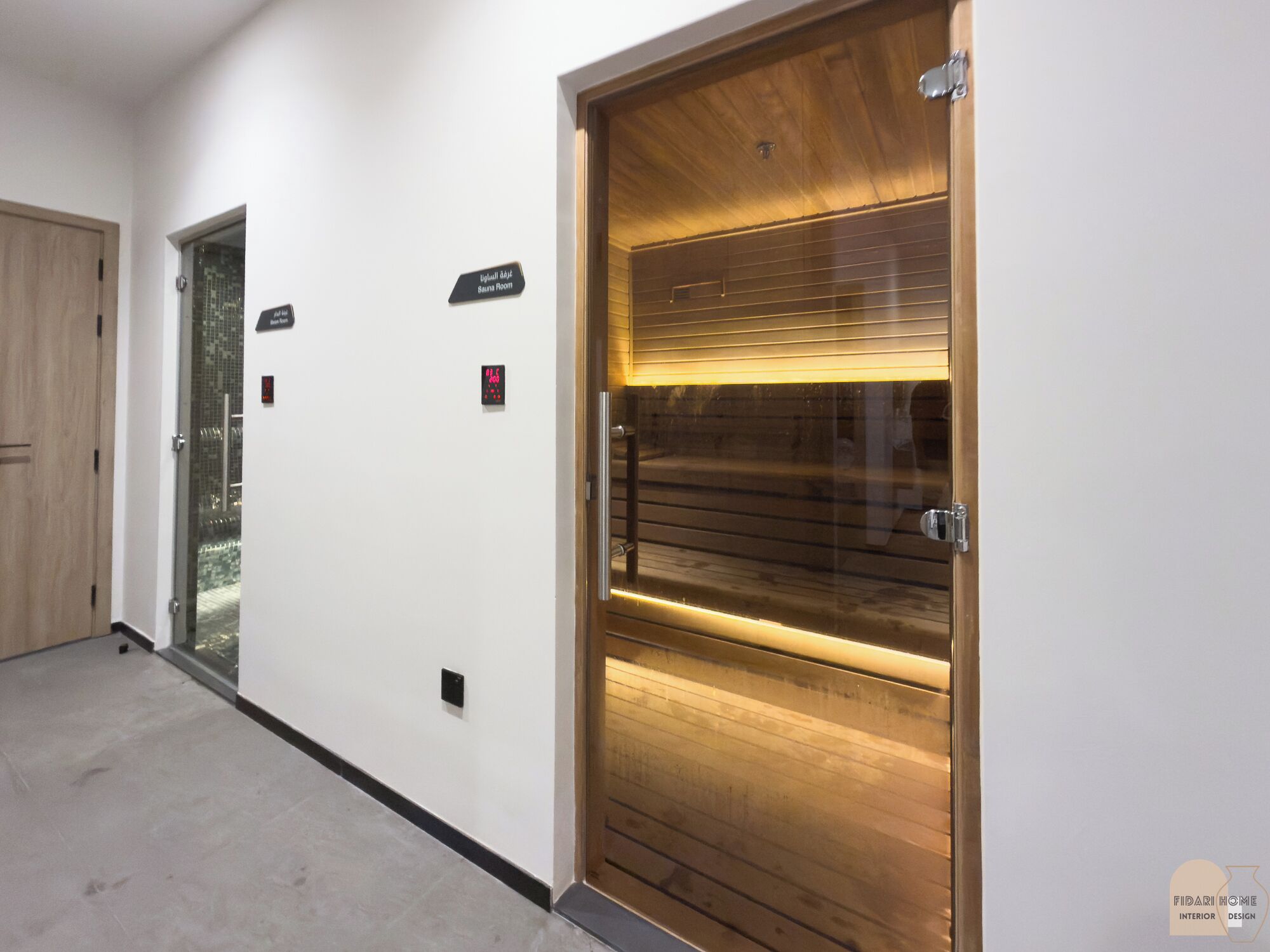 A hallway with a wooden door labeled "Sauna Room" and a glass door labeled "Gym."